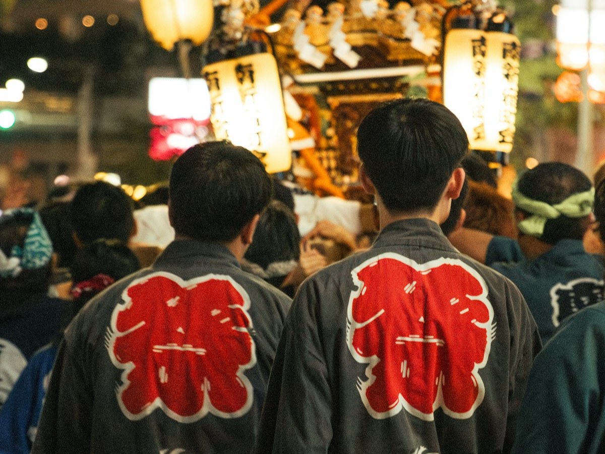 法被を着た担ぎ手と神輿が進む夜の祭り